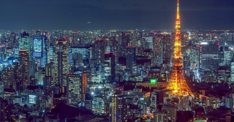 A beautiful aerial shot of modern city architecture with an illuminated tower on the side